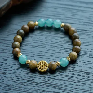 Detailed macro view of green sandalwood beads with jade gourd and gold metal charms