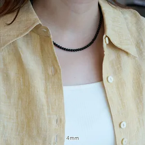 Detail of 4mm natural black agate beaded necklace worn on neck over yellow shirt