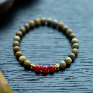 Macro shot of green sandalwood beads with red agate charms and golden spacers