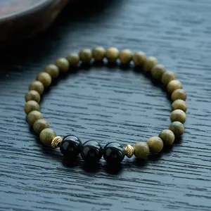 Macro detail of sandalwood beads with black spheres and vintage golden floral spacers