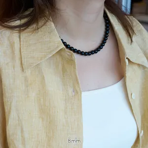 Close-up of 8mm natural black agate beaded necklace worn on neck with linen shirt