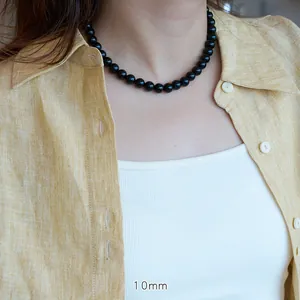 Detail of 10mm natural black agate beads necklace worn on a casual linen shirt
