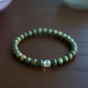 Macro detail of green sandalwood beads with a translucent amber-like gemstone bead