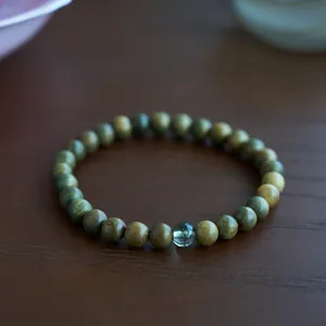Macro view of sandalwood beads with pale green gemstone bead on a wooden table