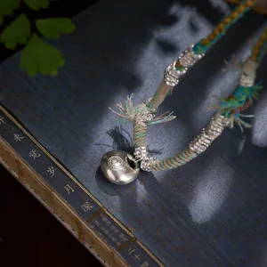Collier ethnique tressé avec pendentif serrure de fortune sur livre ancien