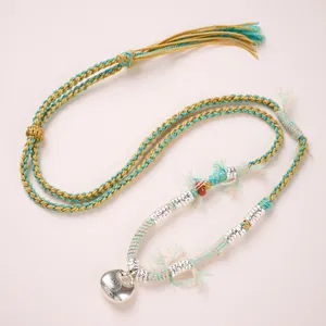 Détail du collier en cordon tressé à la main avec pendentif cœur en argent et perles