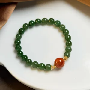 Detailed shot of jasper beaded bracelet with red agate accent on white ceramic tray