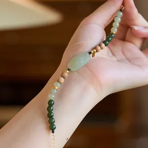 Detail of vintage beaded bracelet with green jasper, amber, and golden metal accents