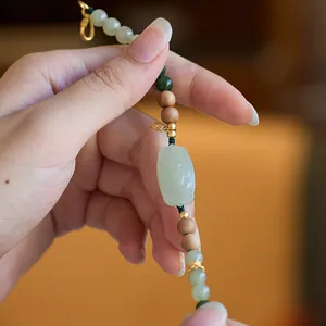 Detail of natural green jasper bracelet with amber beads and engraved gold pendant charm