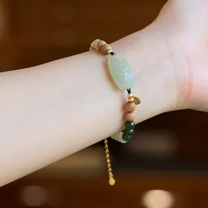 Macro detail of Chinese style jade and wood bead bracelet with gold Fu pendant