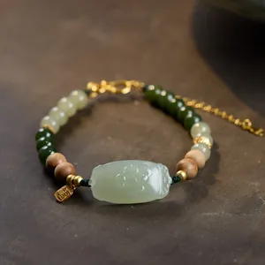 Macro detail of jasper beaded bracelet with gold Fu pendant and carved jade plate