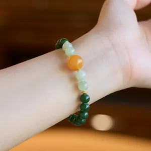 Detail of natural green jasper and amber bead bracelet with ornate gold floral spacers