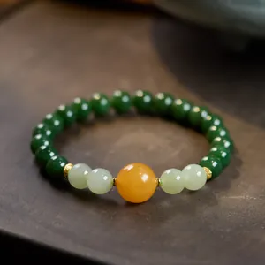 Macro shot of natural jasper beads with amber accents and gold spacers on wood
