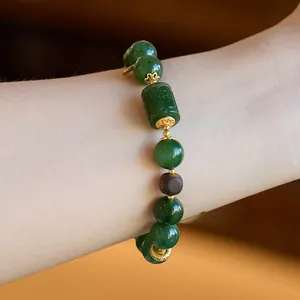 Close-up of a jasper and beeswax bracelet with a carved jade cylinder and wooden beads