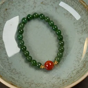 Close-up of natural jasper bead bracelet with red amber accent in a celadon bowl