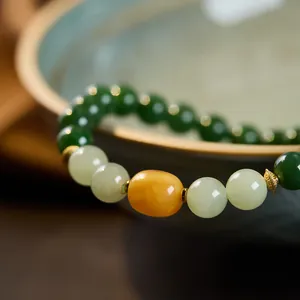 Close-up of natural jasper beads bracelet with golden carved spacers and amber accents