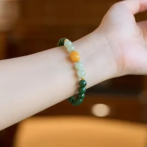 Detail of natural jasper and beeswax bead bracelet worn on wrist with gold metal spacers