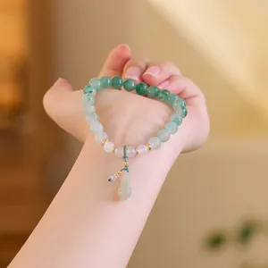 Jade-Perlenarmband in Grün und Weiß mit Tropfenanhänger und goldenen Akzenten am Handgelenk