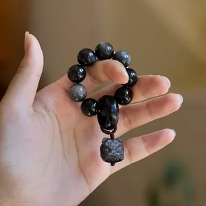 Dettaglio delle perle in ossidiana d'argento naturale e ciondolo con creatura mitologica