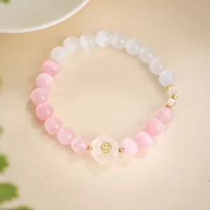 Close-up of cat eye stone bead bracelet with pink and white beads and flower charm