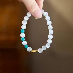 Minimalist cat eye bead bracelet with turquoise accents and a golden fish charm pendant