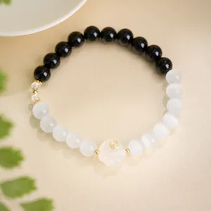 Detailed shot of cat's paw charm bead bracelet with black obsidian and white cat-eye stones
