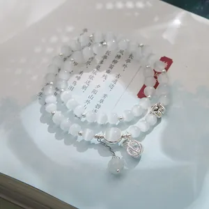 Macro shot of double-layer cat eye stone bead bracelet with silver charms on a book