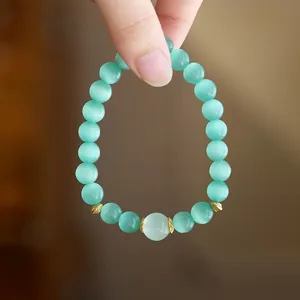 Close-up of a light green cat eye stone beaded bracelet with golden floral accents