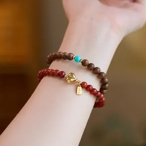 Close-up of stacked red agate and wooden beaded bracelets with a gold heart pendant