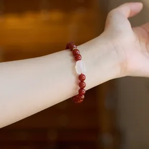 Detail of red agate beaded bracelet on wrist with pink translucent stone and gold bead