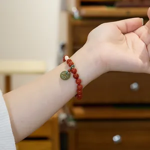 Macro shot of red agate beads with a green jade pendant and white pearl on a female wrist