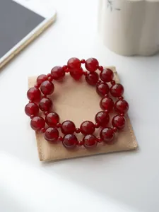 Makroaufnahme von zweilagigem rotem Achatperlenarmband auf einem Schmuckbeutel aus Wildleder