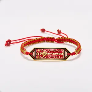 Détail macro du bracelet tressé rouge avec breloque émaillée Tai Sui dorée et perles