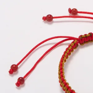 Bracelet tressé main rouge et doré avec perles d'agate rouge sur fond blanc pur
