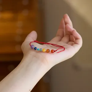Nahaufnahme eines roten Armbands mit sieben bunten natürlichen Chakra-Steinperlen