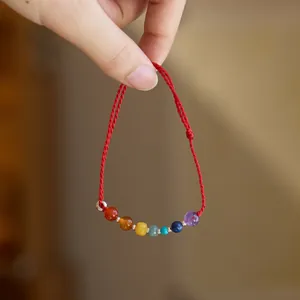 Detailansicht des roten geflochtenen Armbands mit sieben bunten Chakra-Perlen