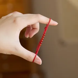 Nahaufnahme des roten geflochtenen Glücksarmbands mit sechs runden Perlen und Knotenzug