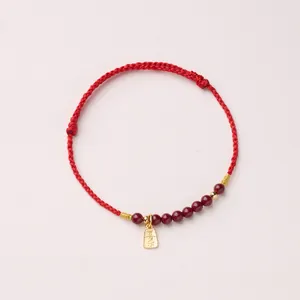 Nahaufnahme des roten geflochtenen Armbands mit Achatperlen und goldenem Anhänger