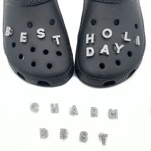 Silver crystal alphabet charms for clogs featuring shiny rhinestones on a black shoe