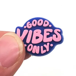 Dettaglio dell'accessorio per zoccoli in PVC Good Vibes Only tenuto tra le dita