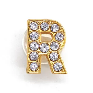 Close-up of golden alloy letter R shoe charm with sparkling rhinestones and rubber backer
