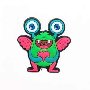 Close-up of cute green monster shoe charm with pink heart and wings for DIY garden clogs