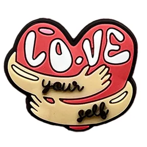 Detail of heart-shaped PVC shoe charm with Love Yourself slogan for garden clogs