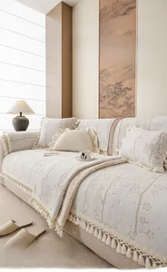 Détail de housse de canapé en velours de lait crème avec motifs floraux et franges
