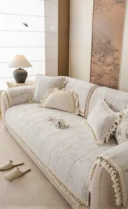 Détail de la housse de canapé en velours jacquard crème avec motifs floraux et franges