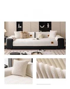Detail of cream white plush sofa cushion featuring striped texture and soft pom-pom trim