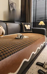 Detail of houndstooth chenille sofa cover with wavy fringe and brown leather trim