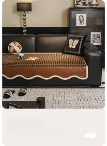 Detail of houndstooth sofa cover with brown leather edge and golden butterfly embroidery