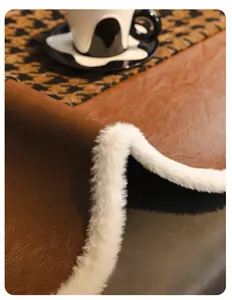 Detail of premium brown faux leather sofa cushion with white faux fur trim and houndstooth texture
