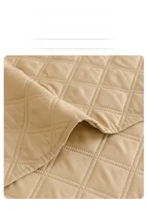Macro shot of khaki quilted cotton fabric showing diamond stitching and wide edge hem